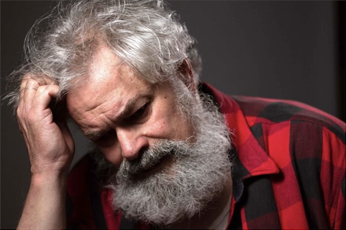 John Dugaw in checked shirt with long bird and while hair